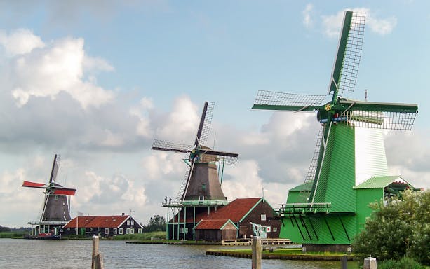 Windmills in the Dutch countryside near a canal, part of a full-day guided tour.