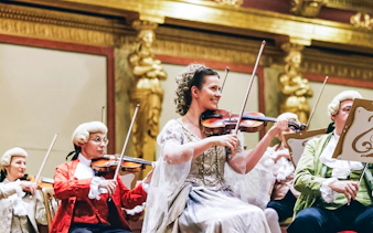 Musicians in period costumes performing at a Mozart orchestra concert.