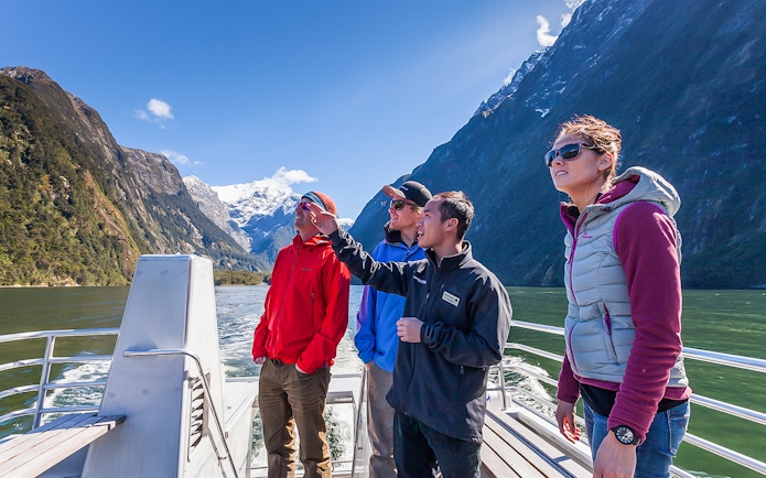 Tourists on a boat tour at Milford Sound with scenic fjord views.