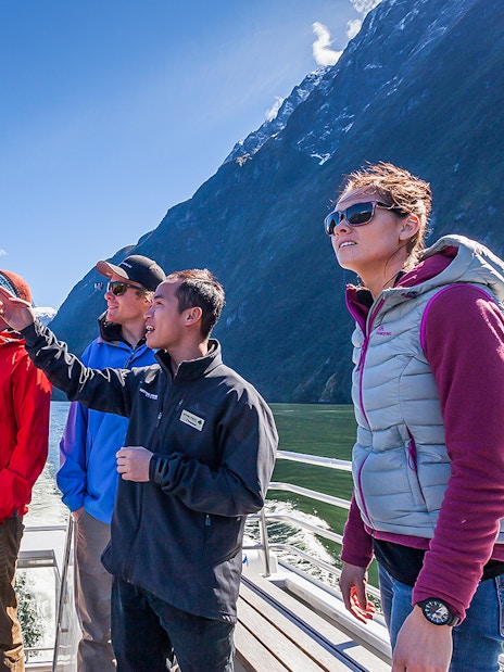 Tourists on a boat tour at Milford Sound with scenic fjord views.