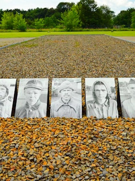 Memorial photos of prisoners at Sachsenhausen Concentration Camp, Germany, with gravel path and trees.