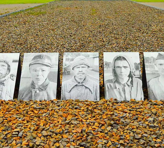 Memorial photos of prisoners at Sachsenhausen Concentration Camp, Germany, with gravel path and trees.