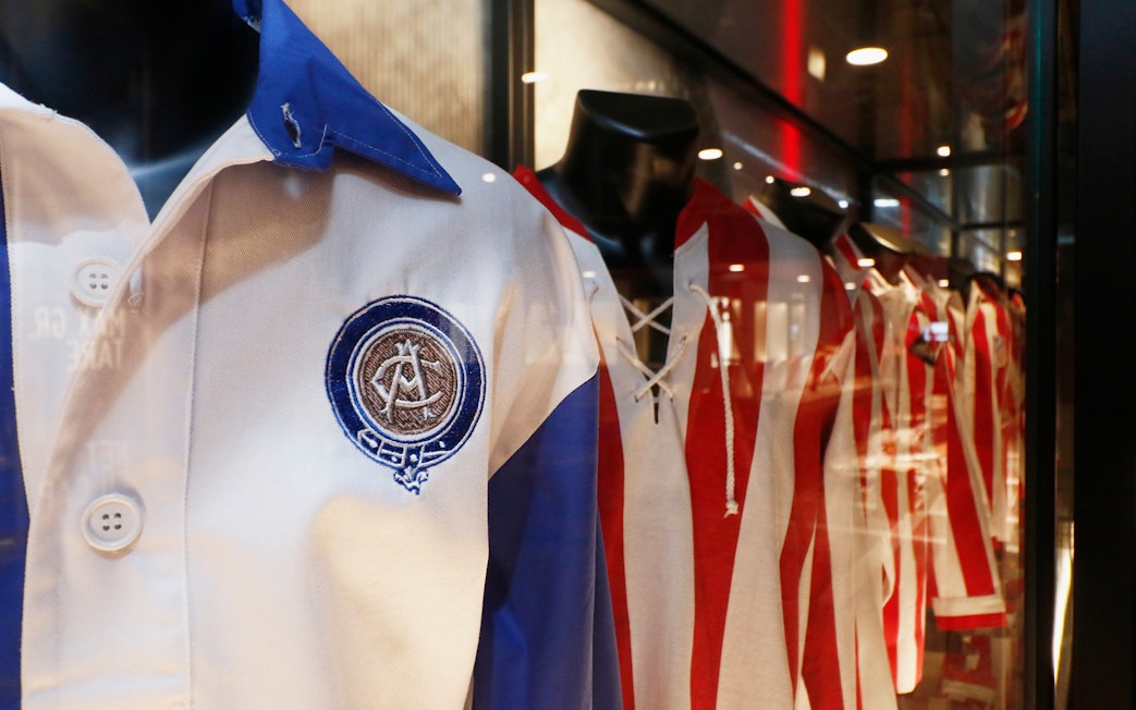 Atlético Madrid jerseys displayed in stadium museum exhibit.