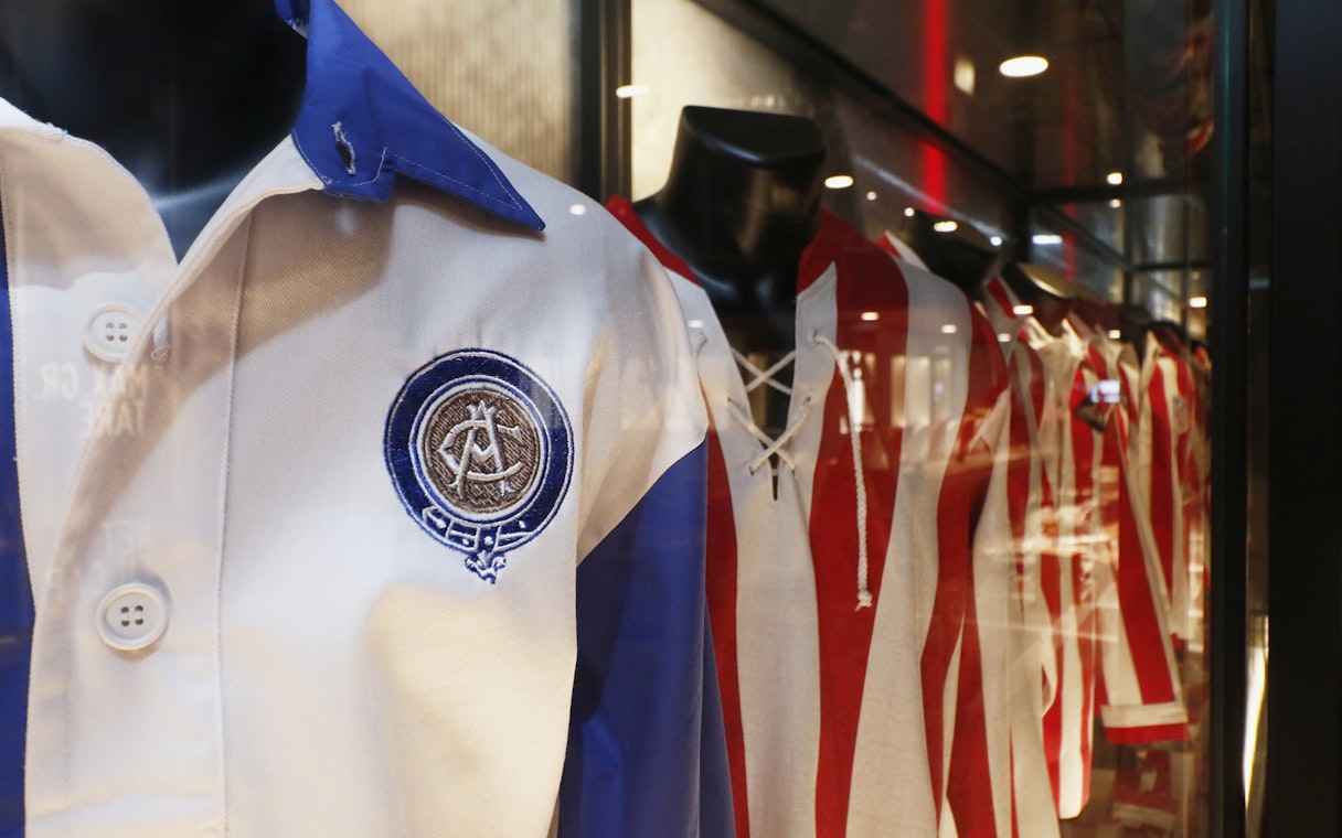 Atlético Madrid jerseys displayed in stadium museum exhibit.