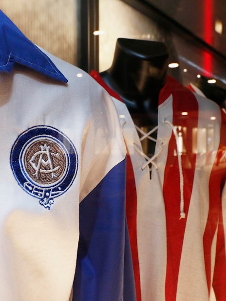 Atlético Madrid jerseys displayed in stadium museum exhibit.