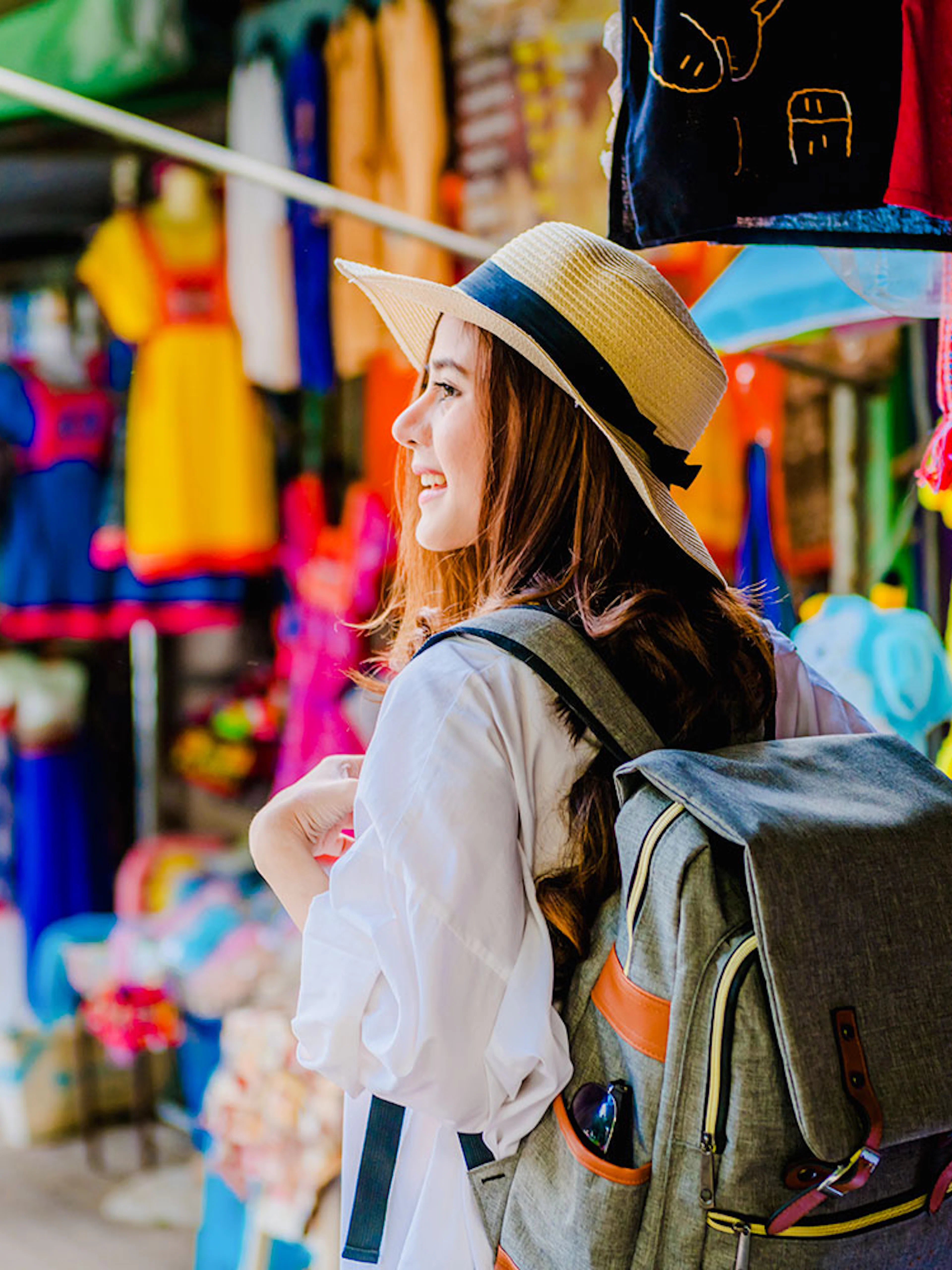 Girl with backpack exploring vibrant market stalls in Doi Suthep, Thailand.