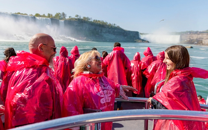 Tourists in red ponchos on a boat approaching Niagara Falls.