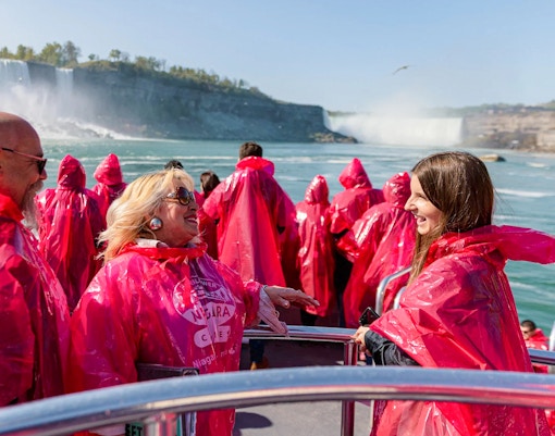 Tourists in red ponchos on a boat approaching Niagara Falls.