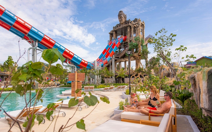 Family relaxing on deck chairs near the Emerald Forest ride at Andamanda Phuket.