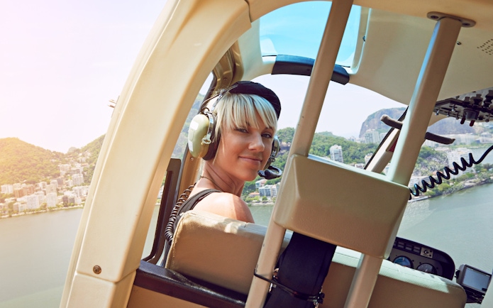 Young woman in helicopter over Rio de Janeiro, view of city and coastline.