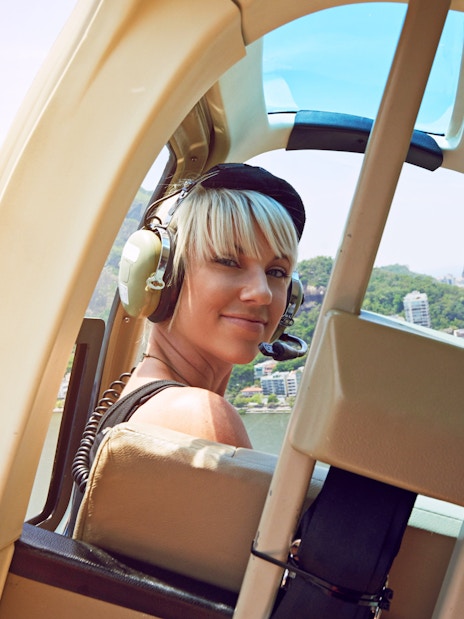 Young woman in helicopter over Rio de Janeiro, view of city and coastline.