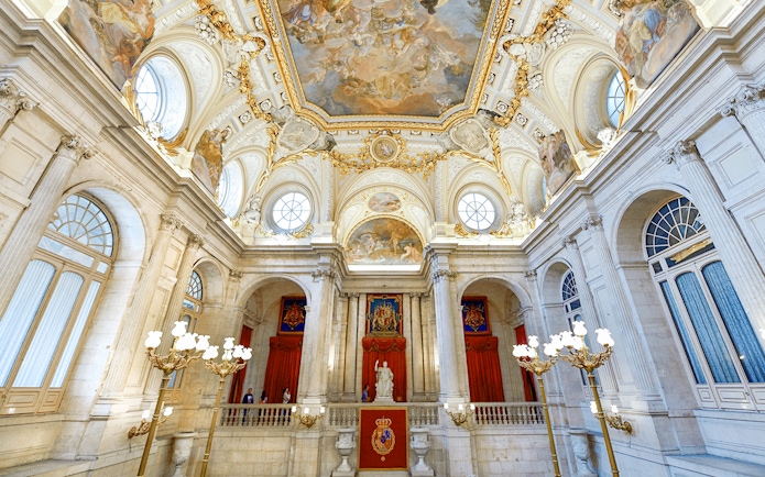 Royal Palace of Madrid interior with ornate ceiling and grand staircase.