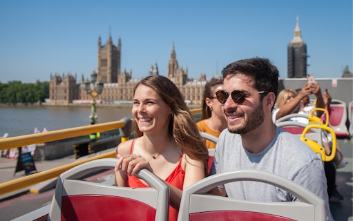 Open-top bus tour in London with view of the Houses of Parliament.