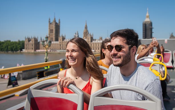 Open-top bus tour in London with view of the Houses of Parliament.