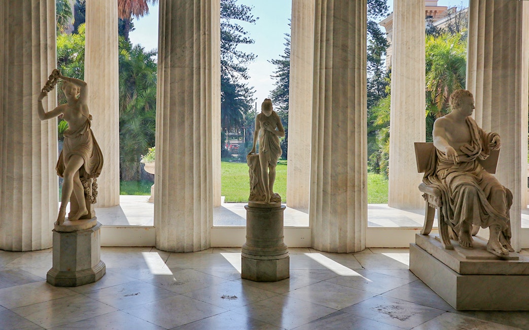 Statues inside Villa Pignatelli, Naples, with garden view through columns.