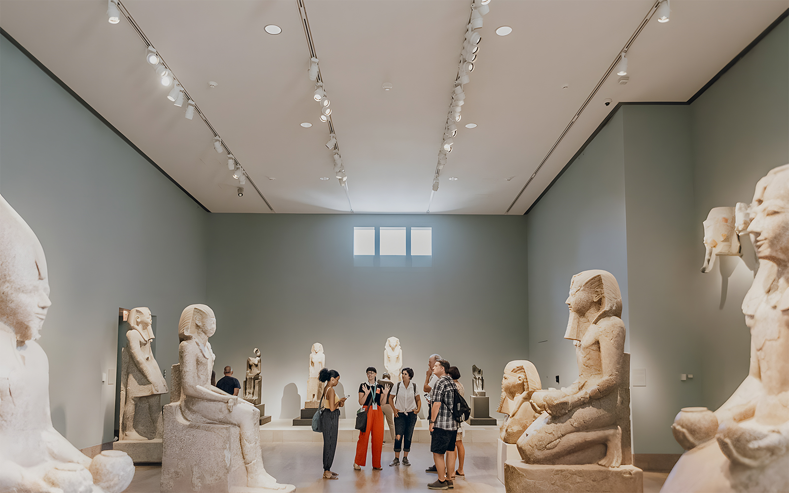 Guide discussing with tourists in the Egyptian art gallery at the Metropolitan Museum of Art.