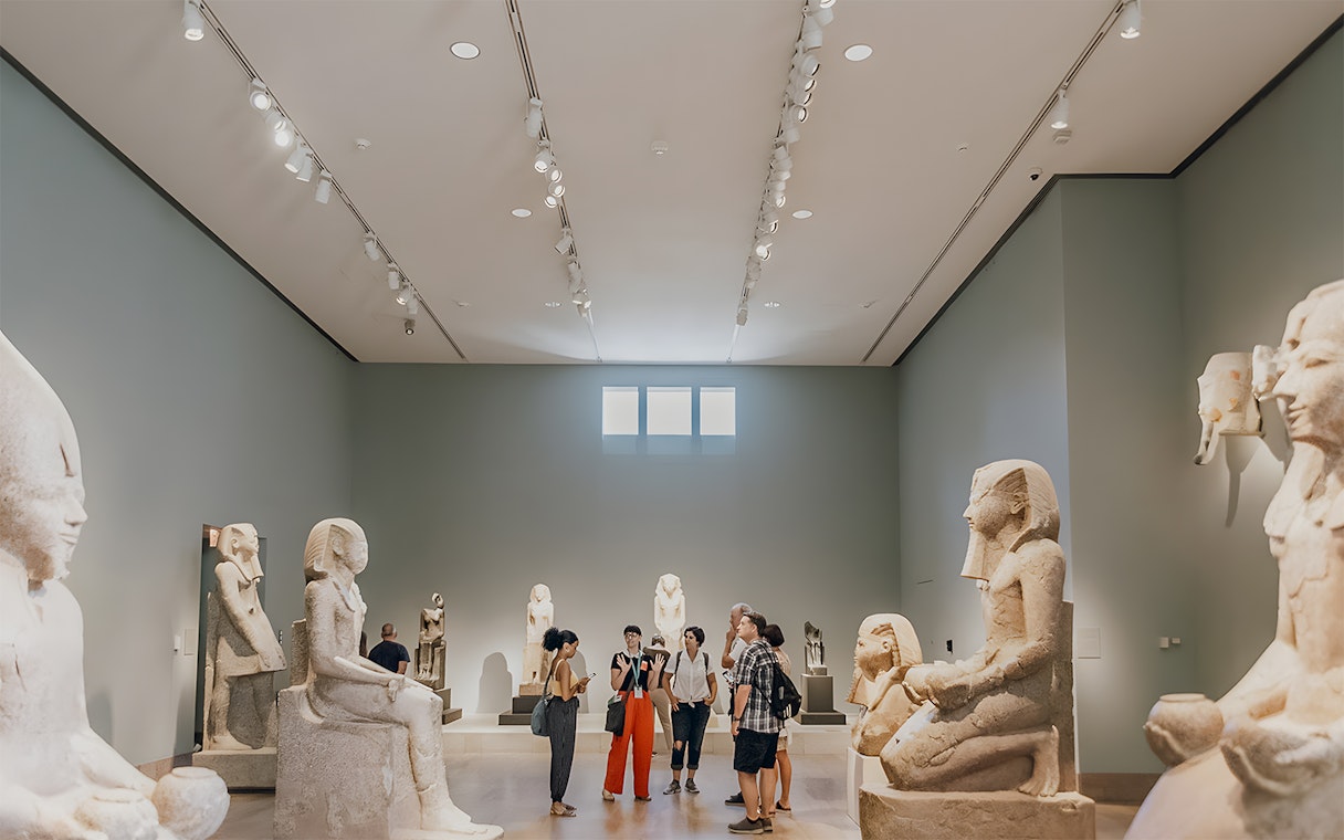 Guide discussing with tourists in the Egyptian art gallery at the Metropolitan Museum of Art.
