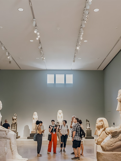 Guide discussing with tourists in the Egyptian art gallery at the Metropolitan Museum of Art.
