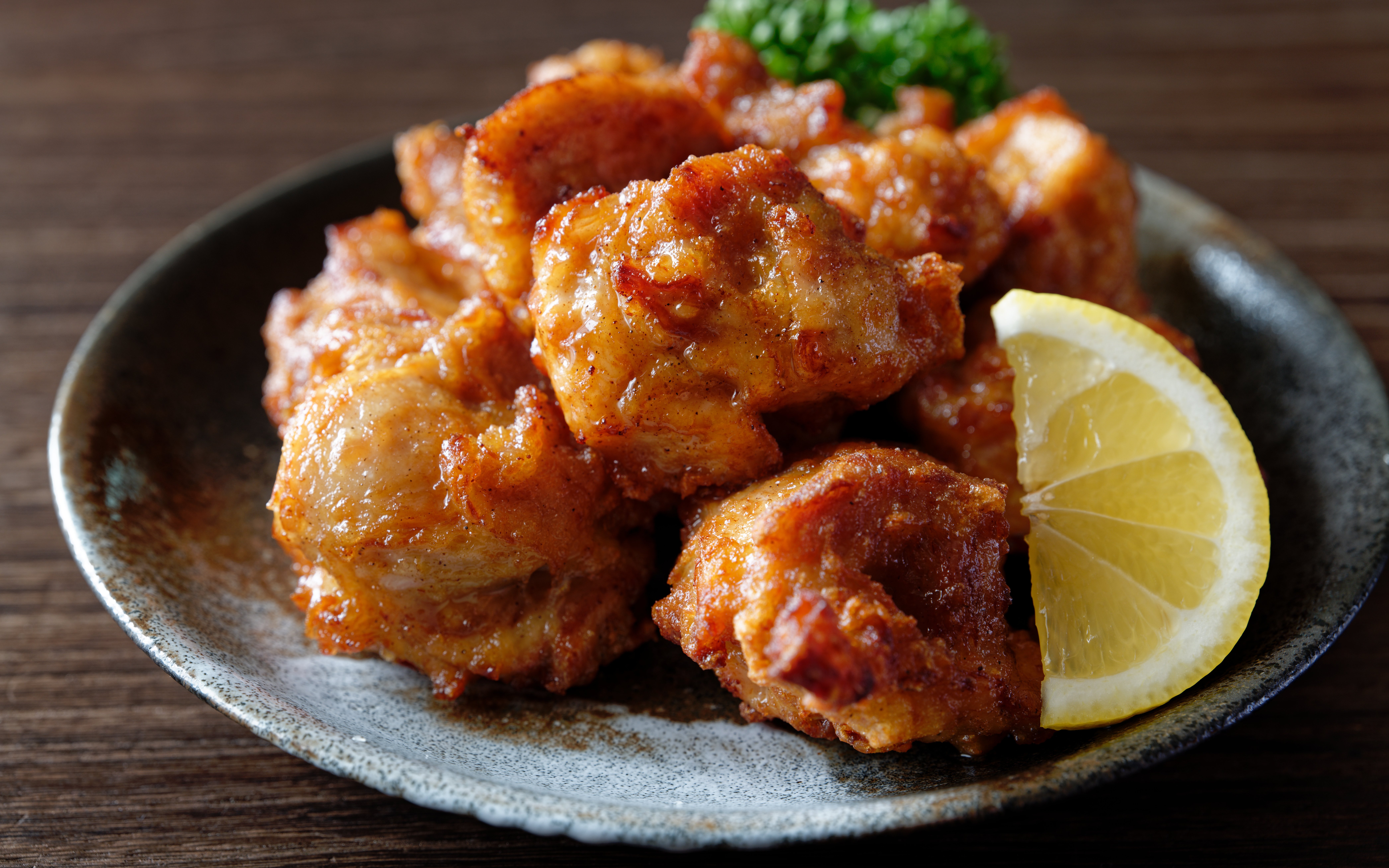 Chicken karaage served with a lime wedge on a ceramic plate.
