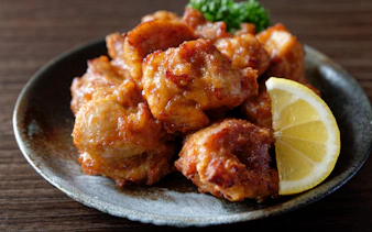 Chicken karaage served with a lime wedge on a ceramic plate.