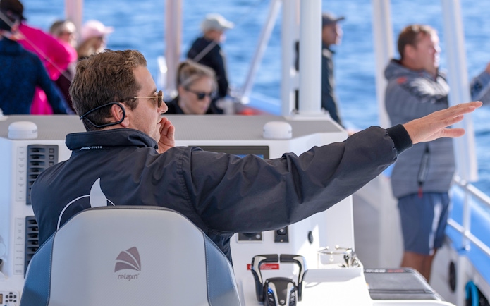 Boat captain guiding passengers on a Gold Coast whale watching tour.