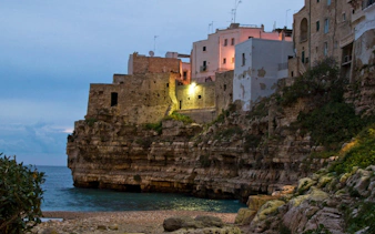 Cliffside buildings in Polignano a Mare at dusk, Valle d'Itria tour from Bari.