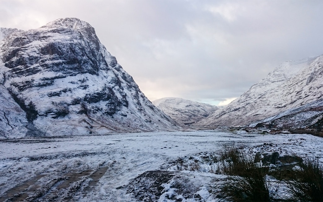 Snow-covered mountains in Glencoe, Scotland during winter.