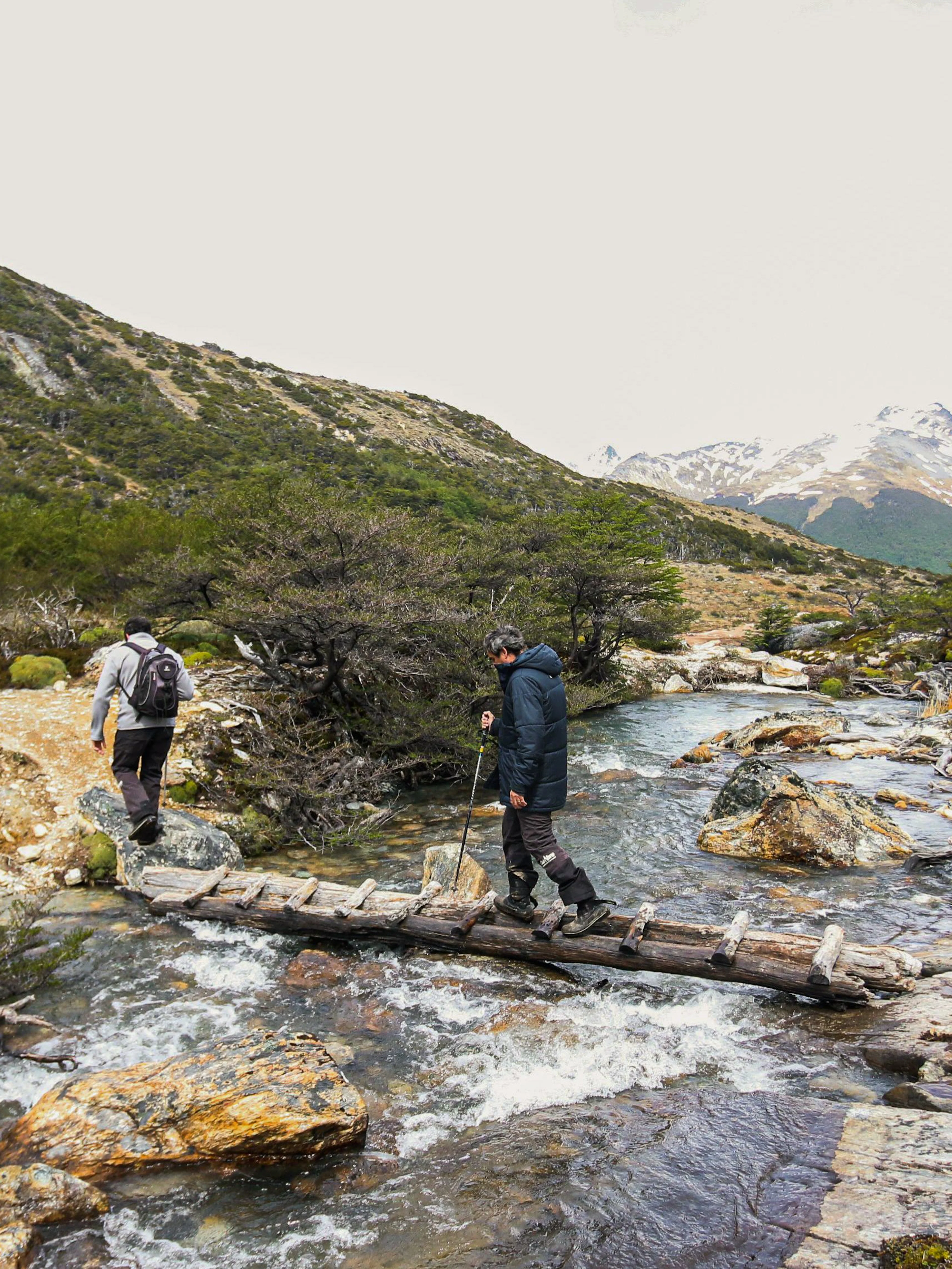 Hikers crossing a wooden bridge over a stream on the Esmeralda Lake Trek in Patagonia.
