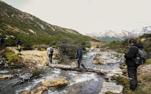 Hikers crossing a wooden bridge over a stream on the Esmeralda Lake Trek in Patagonia.
