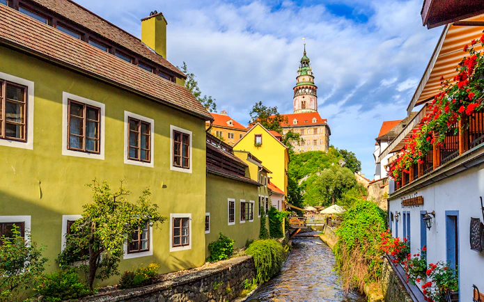 Cesky Krumlov castle tower and colorful buildings along a canal.