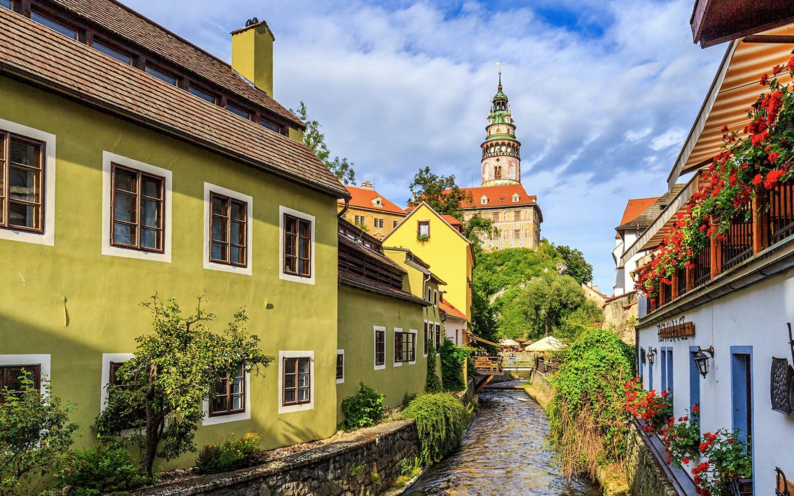 Cesky Krumlov castle tower and colorful buildings along a canal.