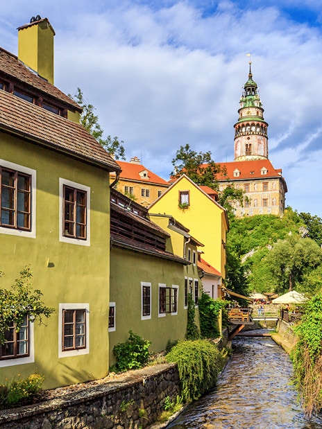 Cesky Krumlov castle tower and colorful buildings along a canal.