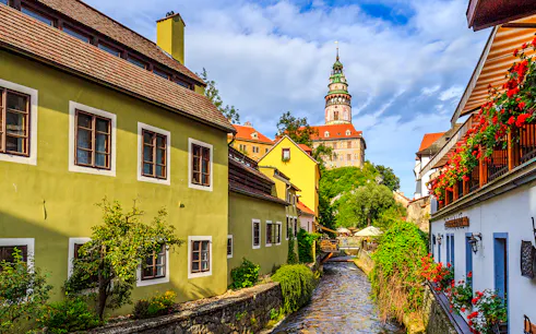 Cesky Krumlov castle tower and colorful buildings along a canal.