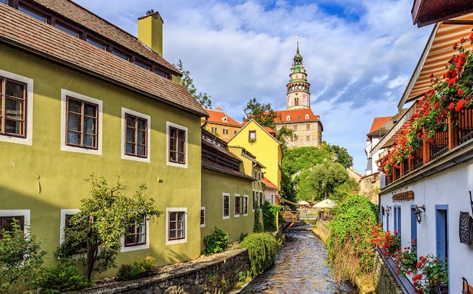 Cesky Krumlov castle tower and colorful buildings along a canal.