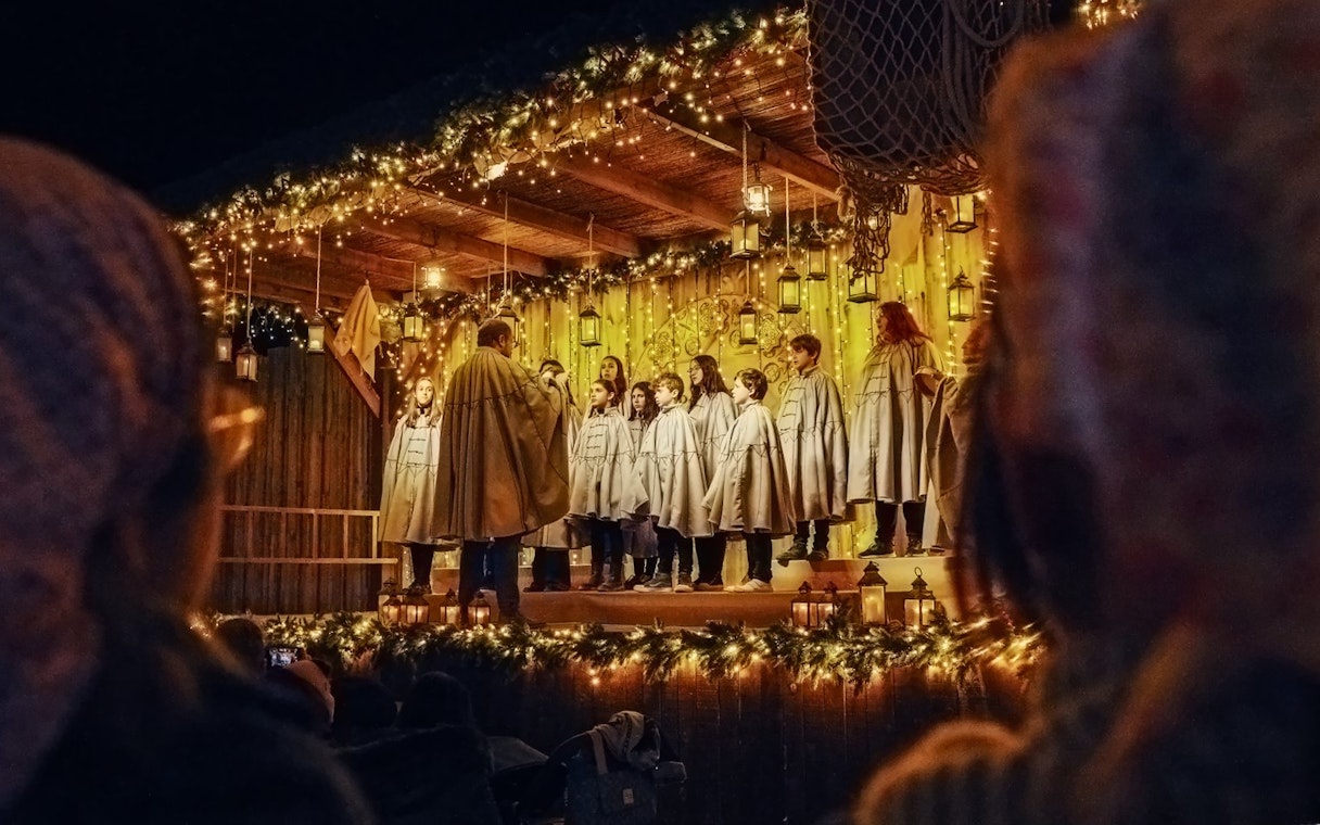 Carol singing show at Puy du Fou España during Christmas with choir on decorated stage.