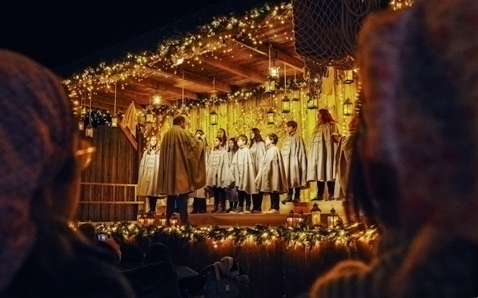 Carol singing show at Puy du Fou España during Christmas with choir on decorated stage.