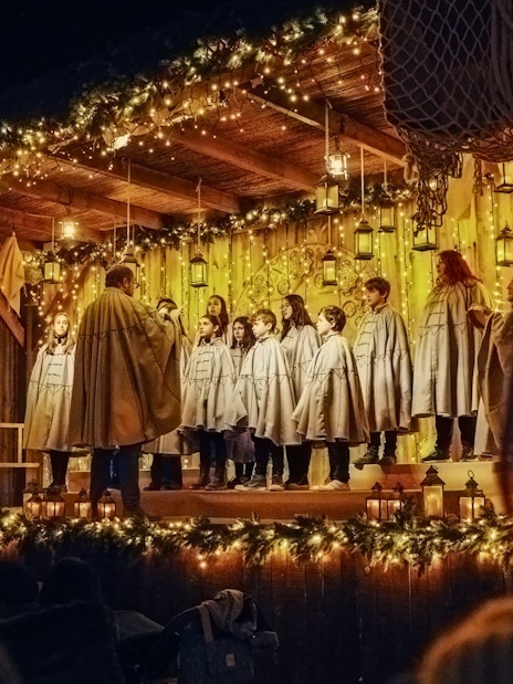 Carol singing show at Puy du Fou España during Christmas with choir on decorated stage.