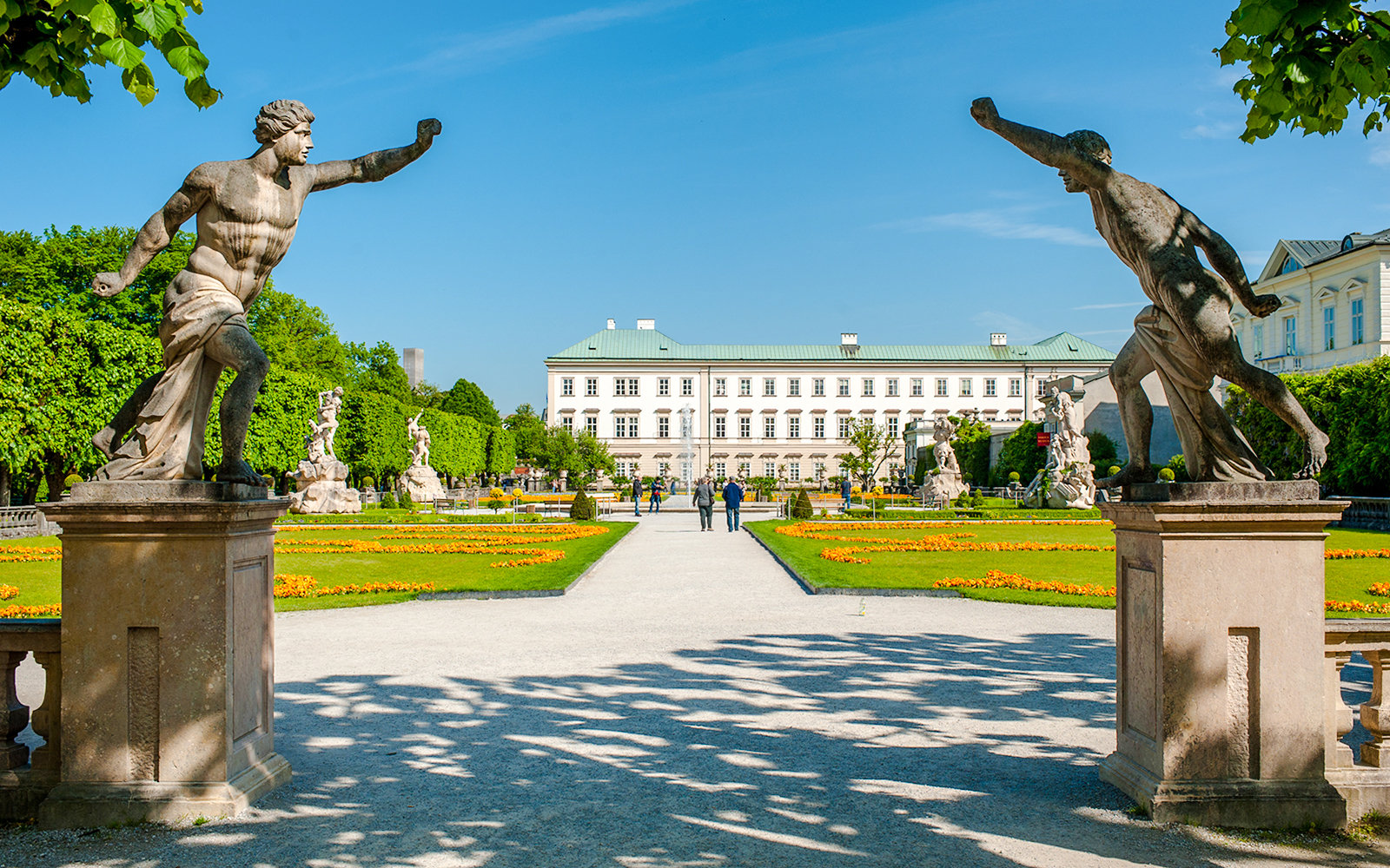 Statues and pathways in Mirabell Gardens with Mirabell Palace, Salzburg in the background.
