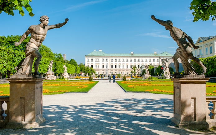 Statues and pathways in Mirabell Gardens with Mirabell Palace, Salzburg in the background.