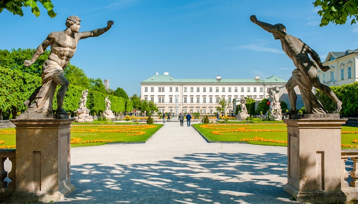 Statues and pathways in Mirabell Gardens with Mirabell Palace, Salzburg in the background.