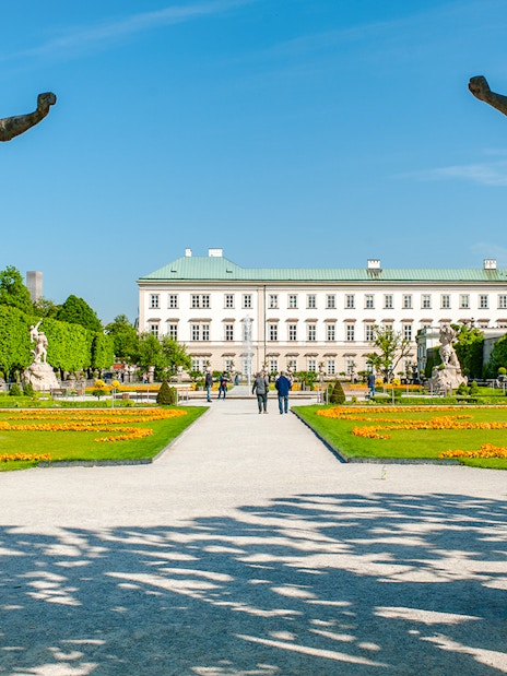 Statues and pathways in Mirabell Gardens with Mirabell Palace, Salzburg in the background.