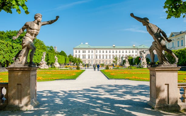 Statues and pathways in Mirabell Gardens with Mirabell Palace, Salzburg in the background.