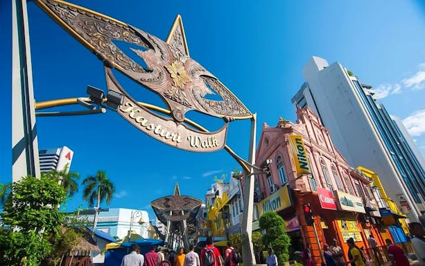 Kasturi Walk entrance in Kuala Lumpur with colorful shops and people exploring the market.