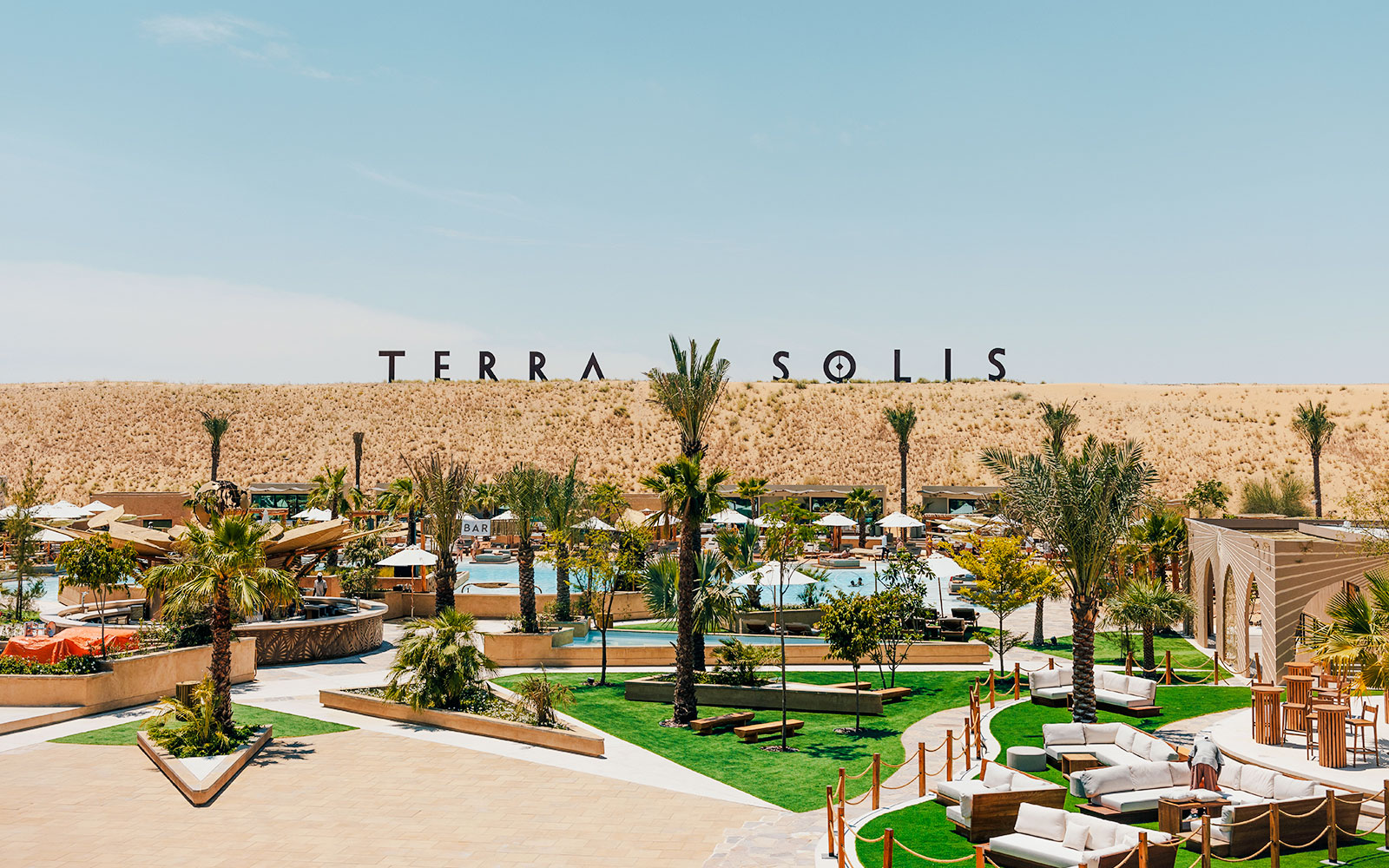 Outdoor view of Terra Solis resort with pool, palm trees, and seating areas in a desert setting.
