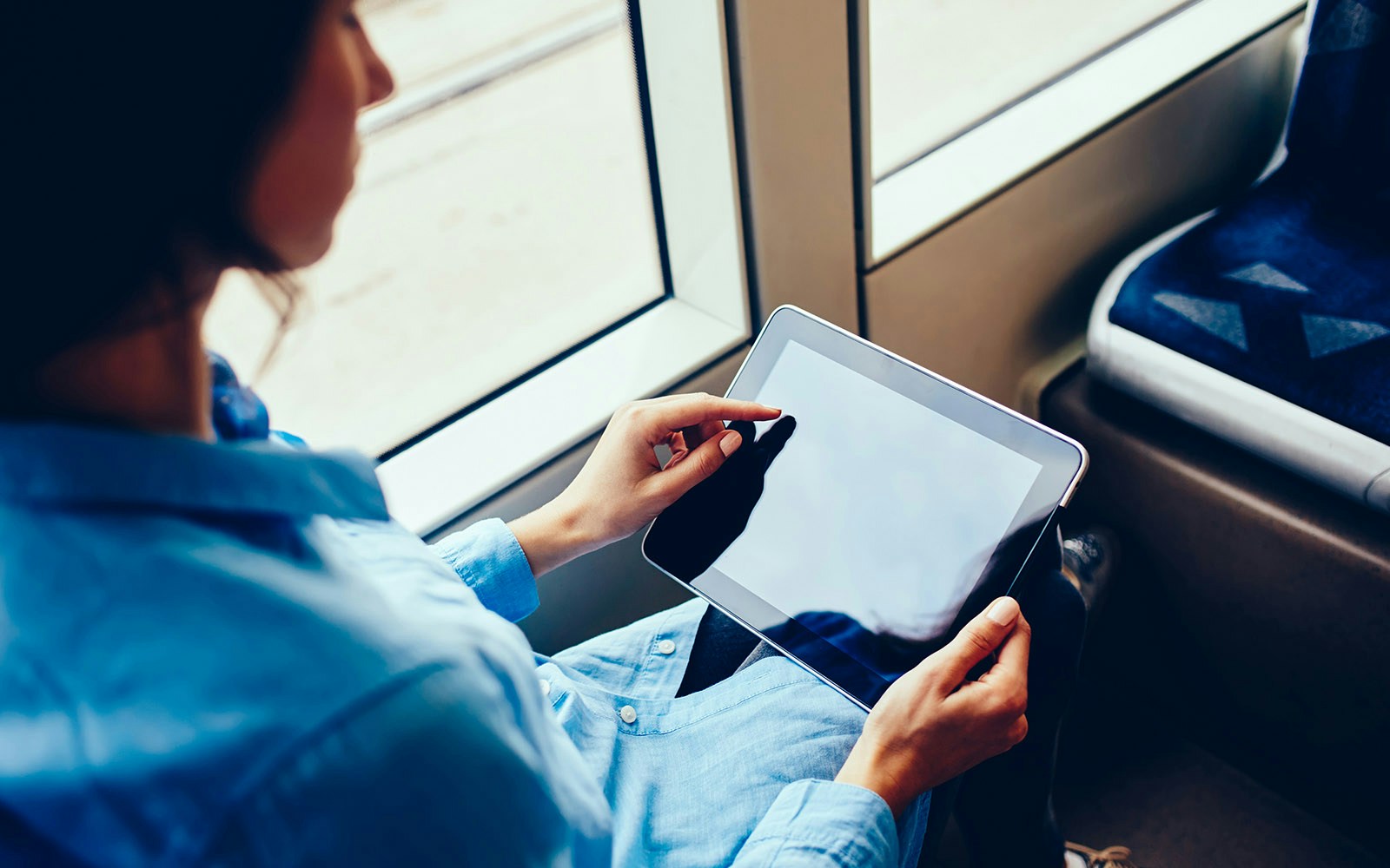 Person using a tablet on a tram, highlighting digital facilities.