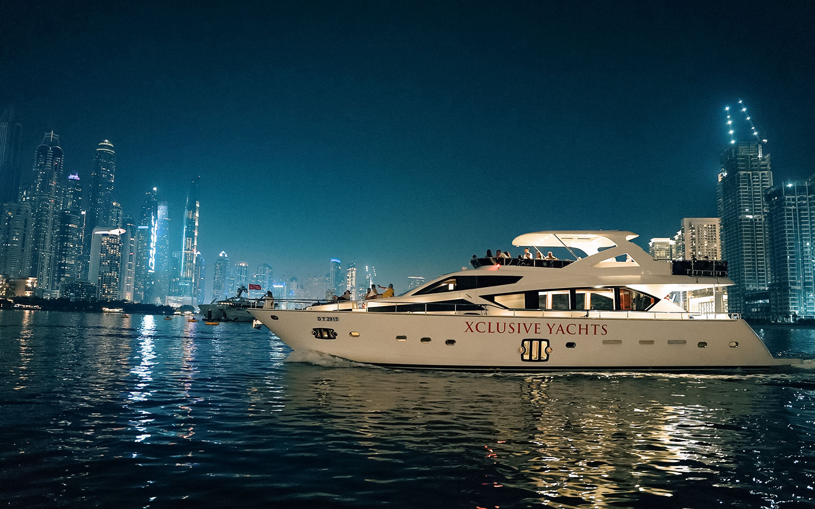 Luxury yacht cruising near Dubai Marina with city skyline in the background.