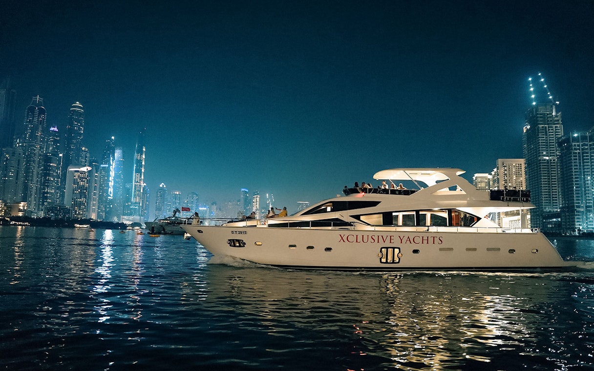 Luxury yacht cruising near Dubai Marina with city skyline in the background.