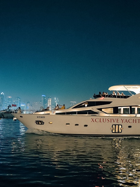 Luxury yacht cruising near Dubai Marina with city skyline in the background.