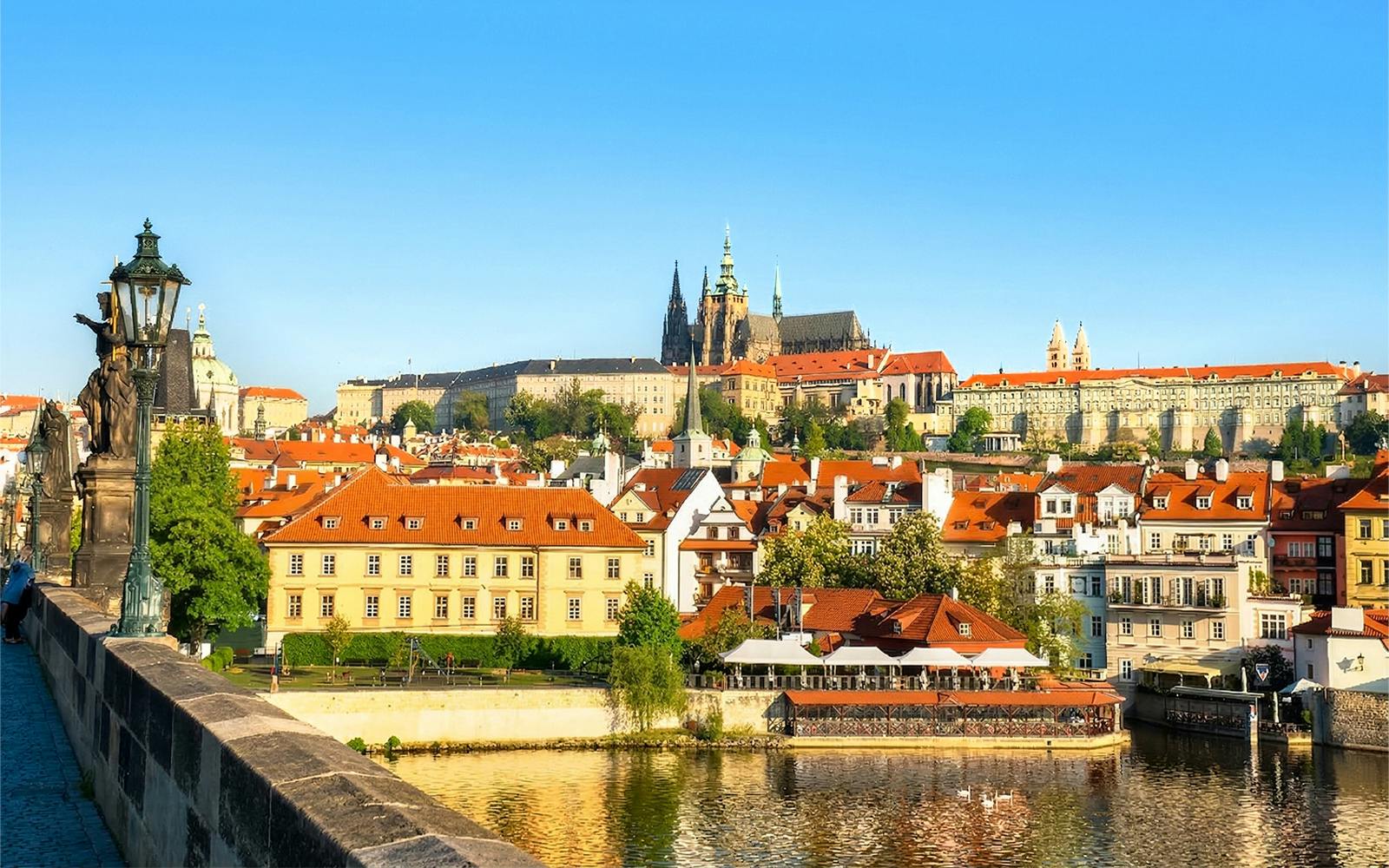 Prague Castle complex viewed from across the Vltava River on a sunny day.