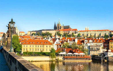 Prague Castle complex viewed from across the Vltava River on a sunny day.